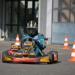 Un conducteur en karting porte un casque vert et bleu