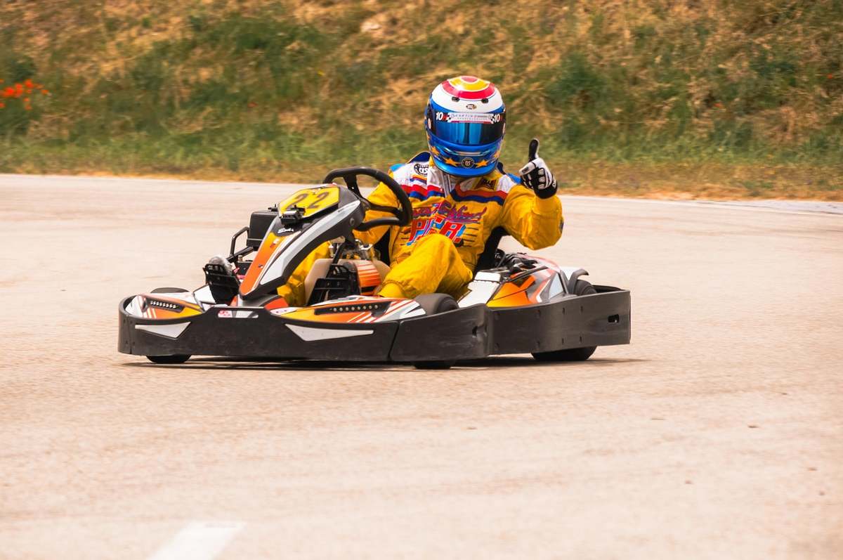 Un pilote casqué au volant d'un kart sur un circuit