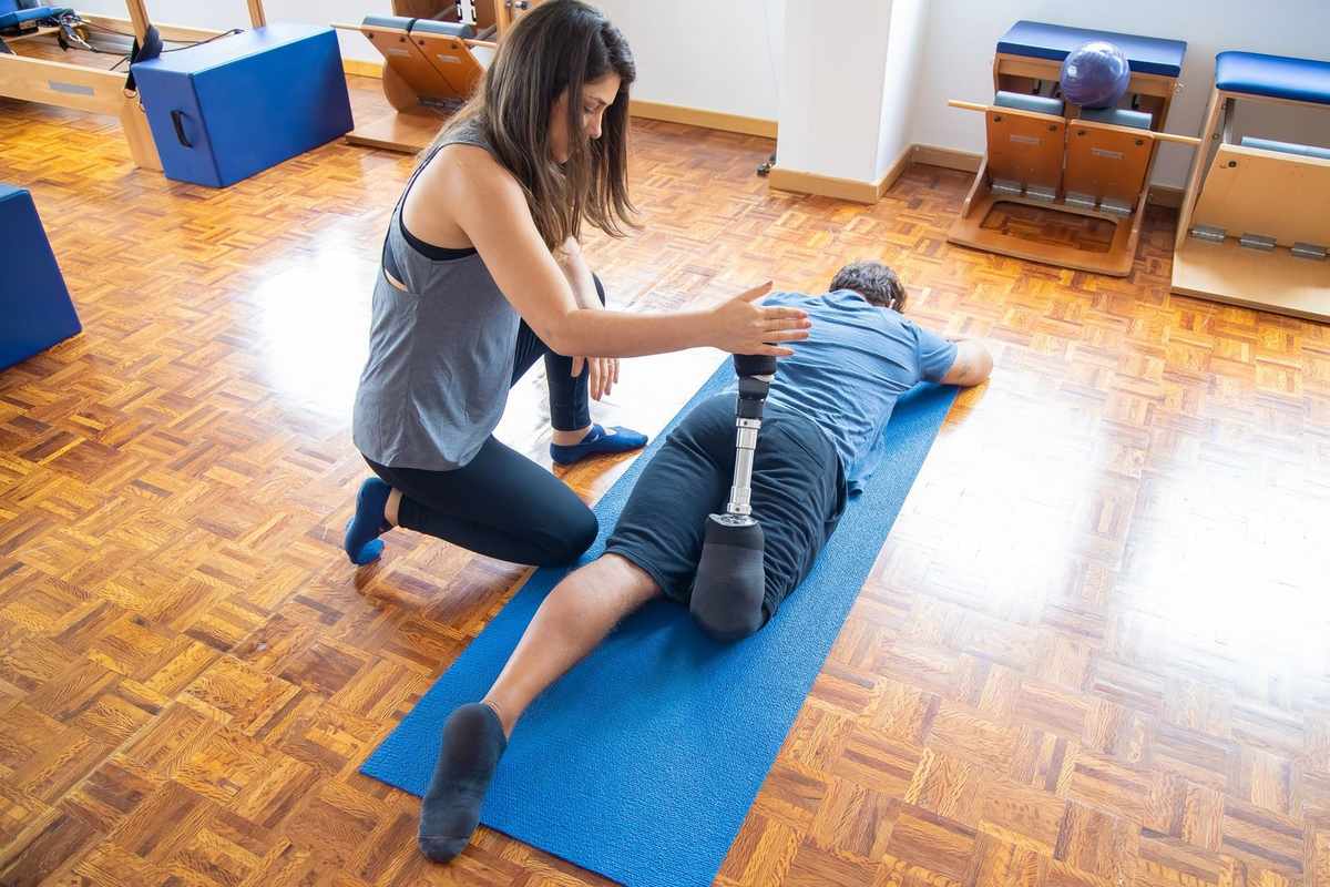 Femme aidant un homme avec une prothèse sur un tapis de yoga