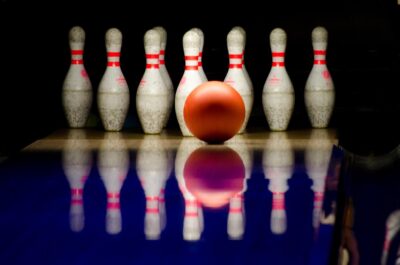Une boule orange prête à frapper dix broches sur une piste sombre