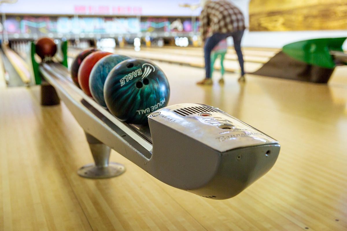 Un joueur de bowling en position de lancer sur une piste