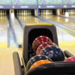 Flacon de boules colorées dans le porte-balles d'une piste de bowling