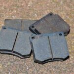 Quatre plaquettes de frein métalliques sur sol granuleux