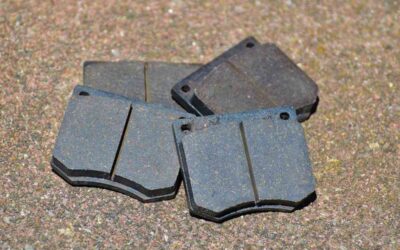 Quatre plaquettes de frein métalliques sur sol granuleux