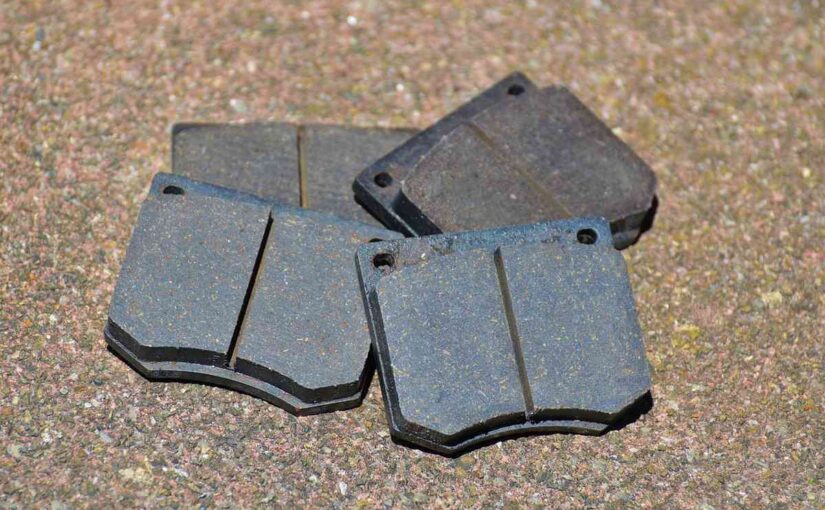 Quatre plaquettes de frein métalliques sur sol granuleux