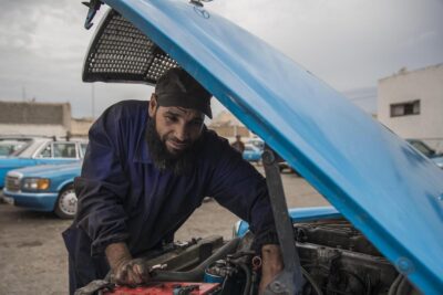 Un mécanicien travaille sous le capot d'une voiture bleue